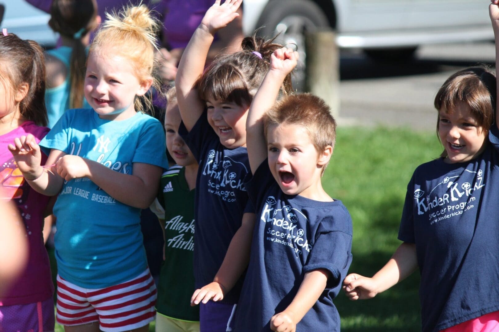 Children cheering outdoors during a group activity.