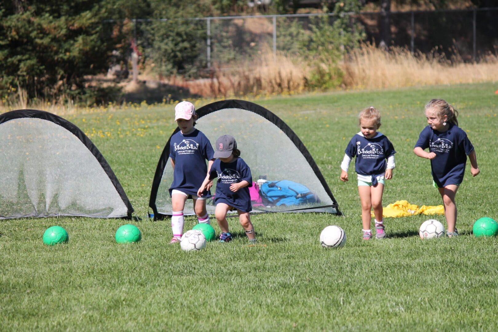 A group of young children playing soccer on the grass.